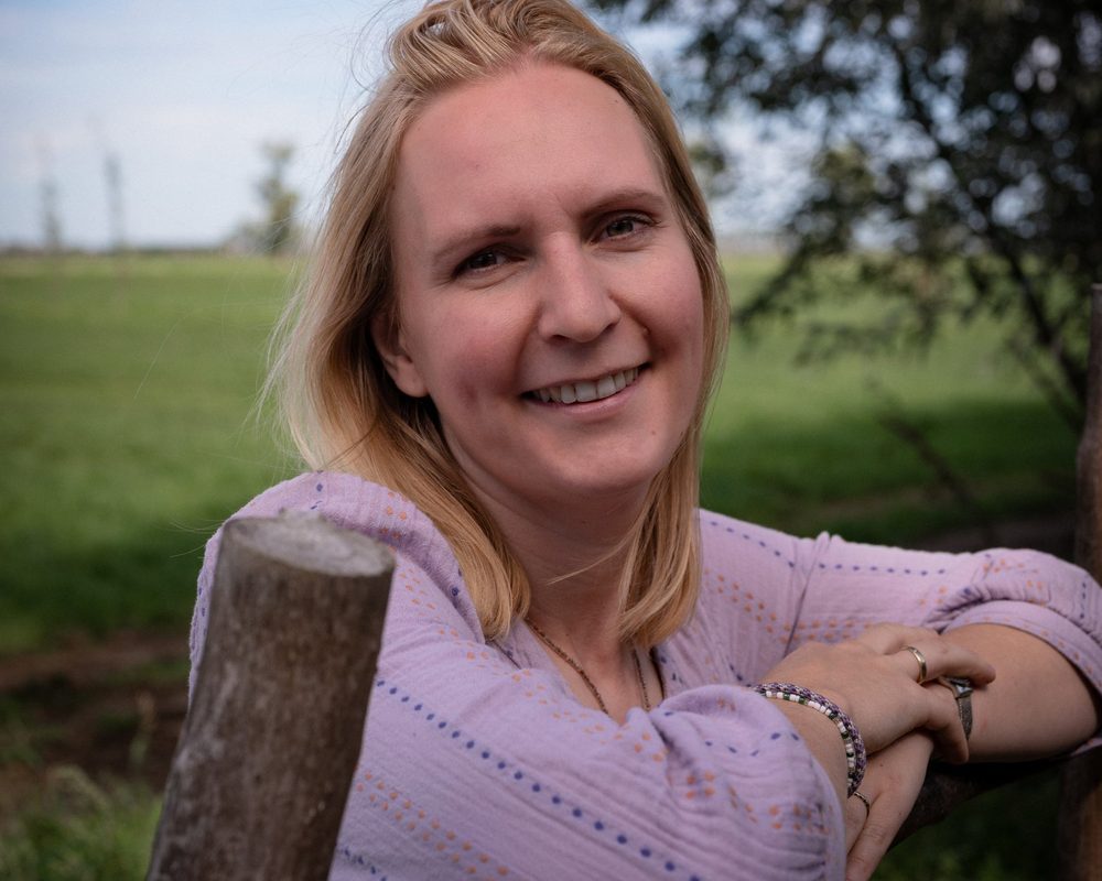Natasja Lammers, klassiek homeopaat, glimlachend bij een weiland